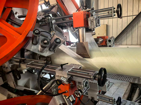 Close-up of fiberglass tape and steel cord tape winding unit on a large bore RTP pipe manufacturing machine..jpg